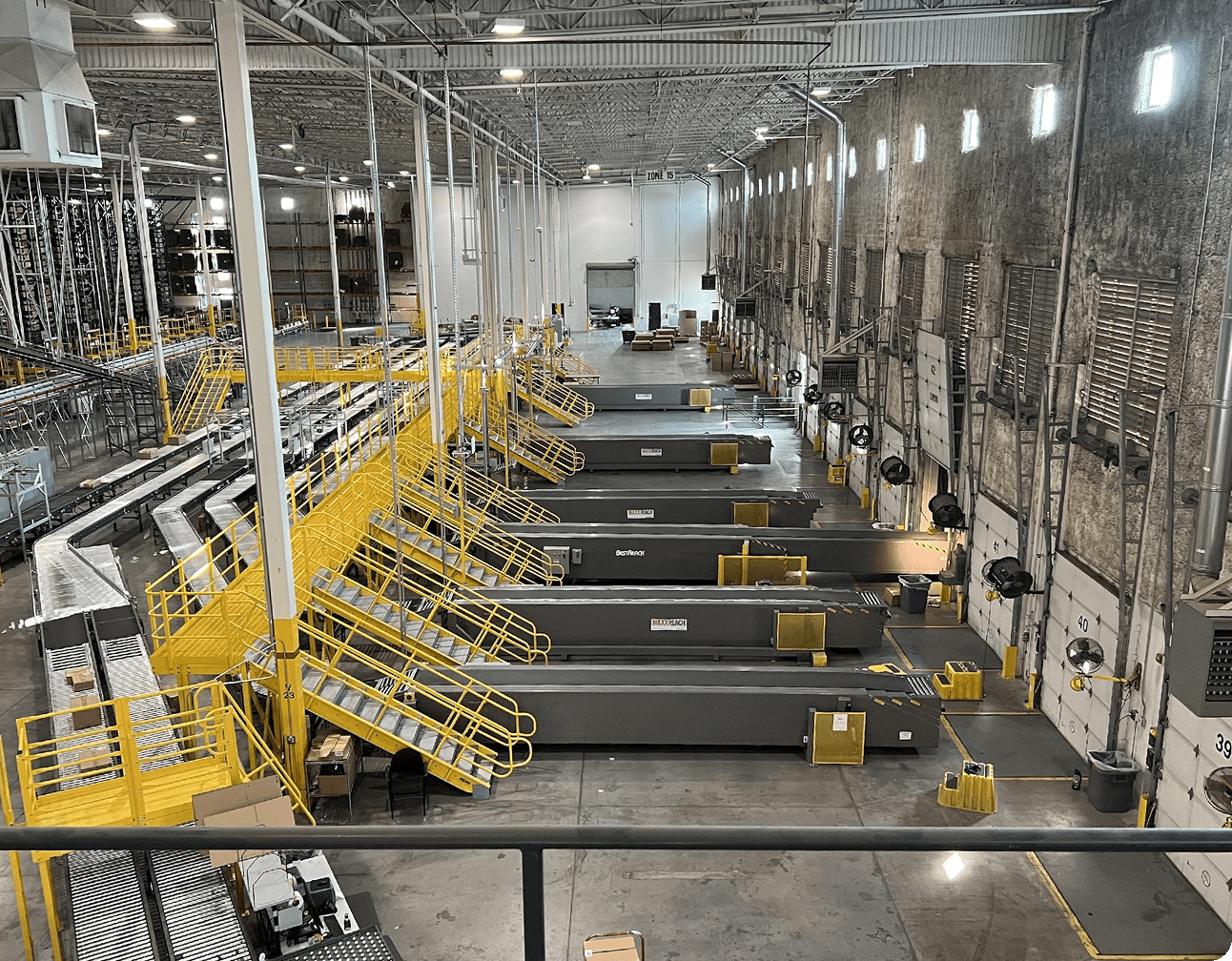 Warehouse sorting floor showing yellow stairways, conveyors running to multiple loading bays and dock areas