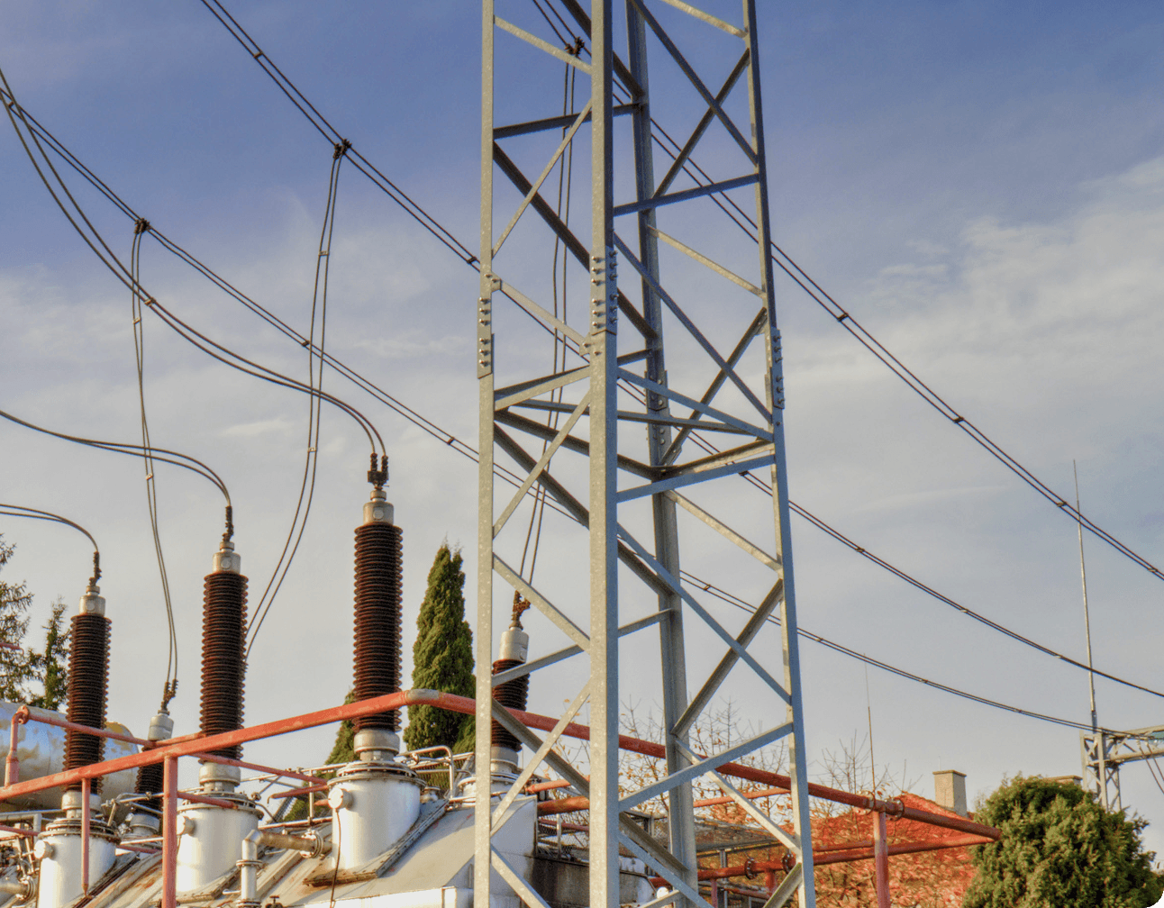 Substation view with porcelain bushings, high-voltage insulators, overhead conductors and lattice transmission tower