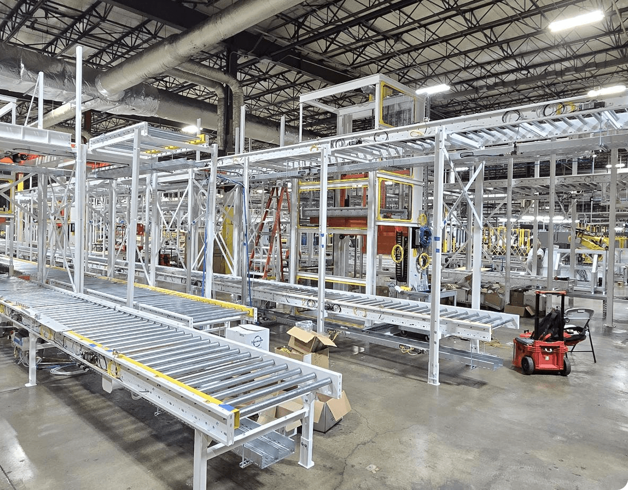 Multi-level roller conveyor installation with metal framing, wiring, sensors, VFD panels and safety devices in factory