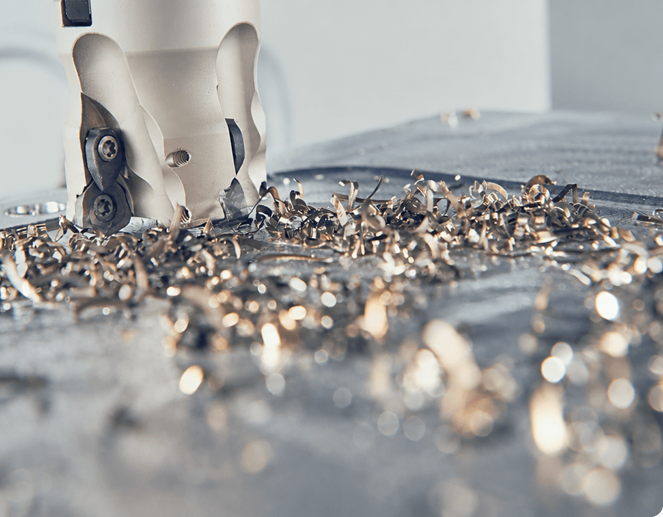 CNC milling cutter and curled metal shavings on a machine table during industrial maintenance at a manufacturing site