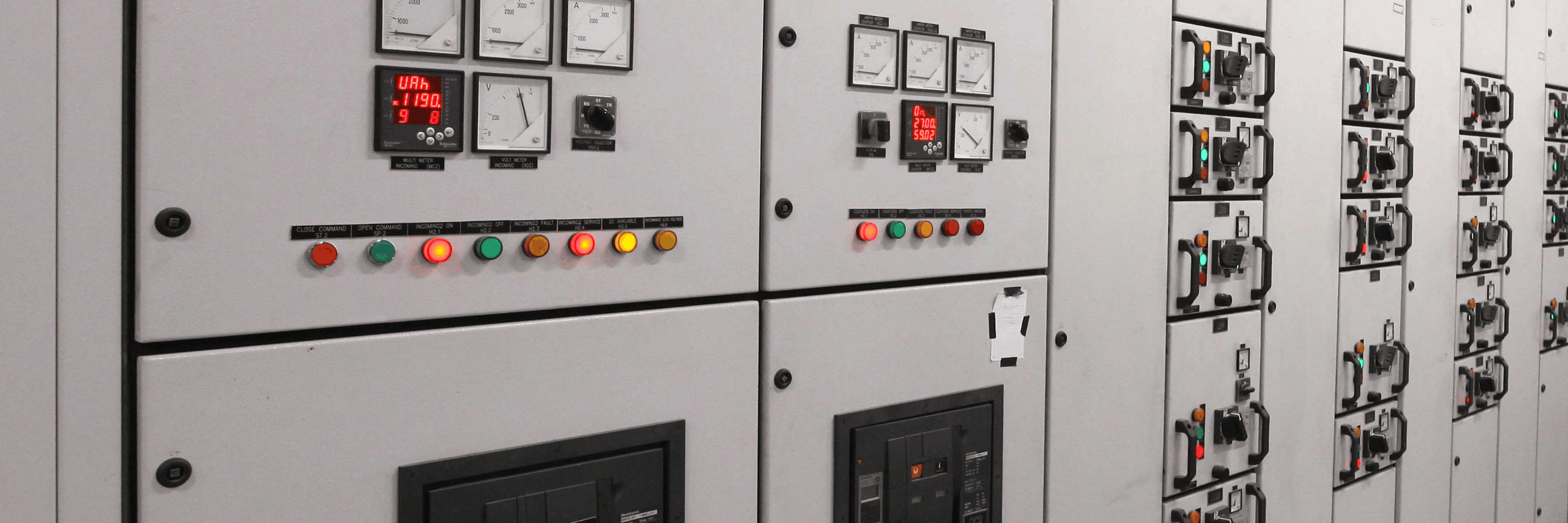 Row of industrial switchgear cabinets showing meters, digital readouts, indicator lights and panel handles in a power room