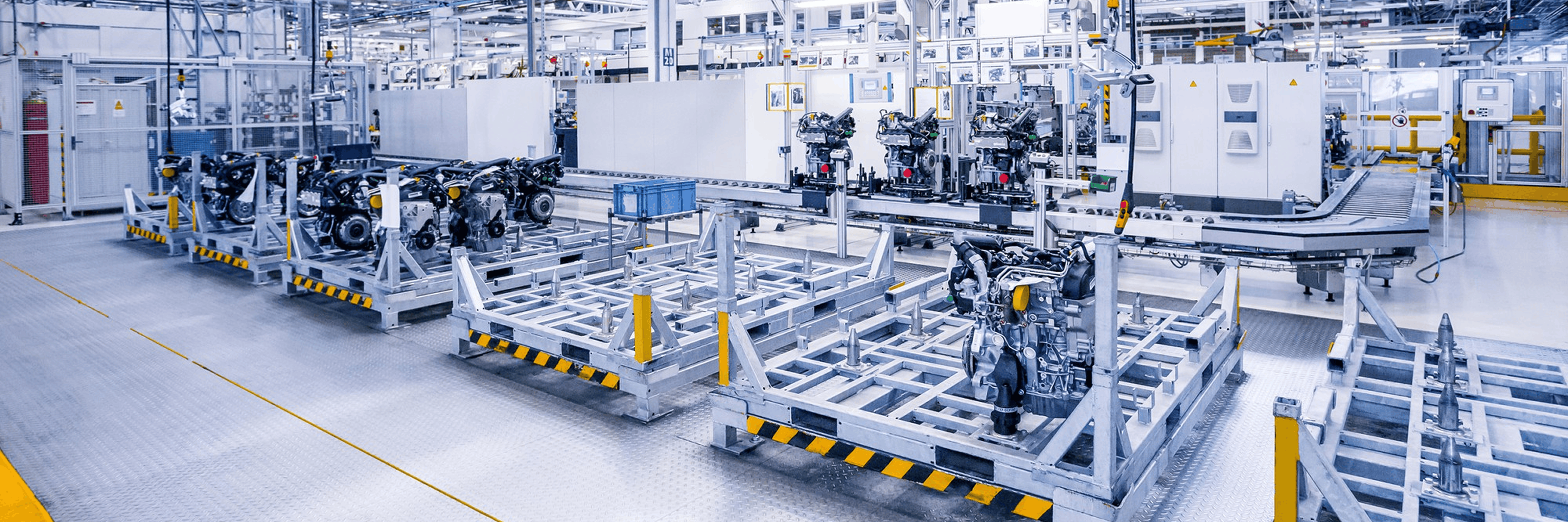 Assembly-line industrial facility with engine blocks mounted on metal pallets, conveyors and factory automation equipment
