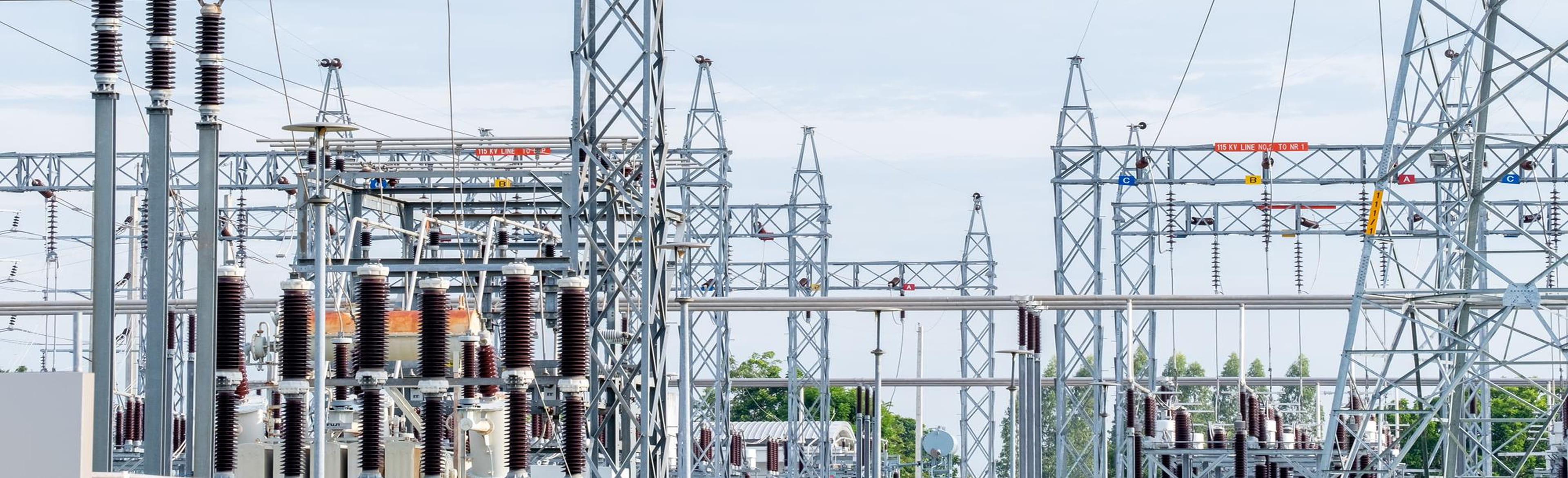 Electrical substation showing power transformers, porcelain bushings, lattice transmission towers and interconnected buswork