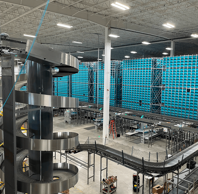 Material handling system showing spiral chute, long conveyors and high-density blue automated storage racks in warehouse