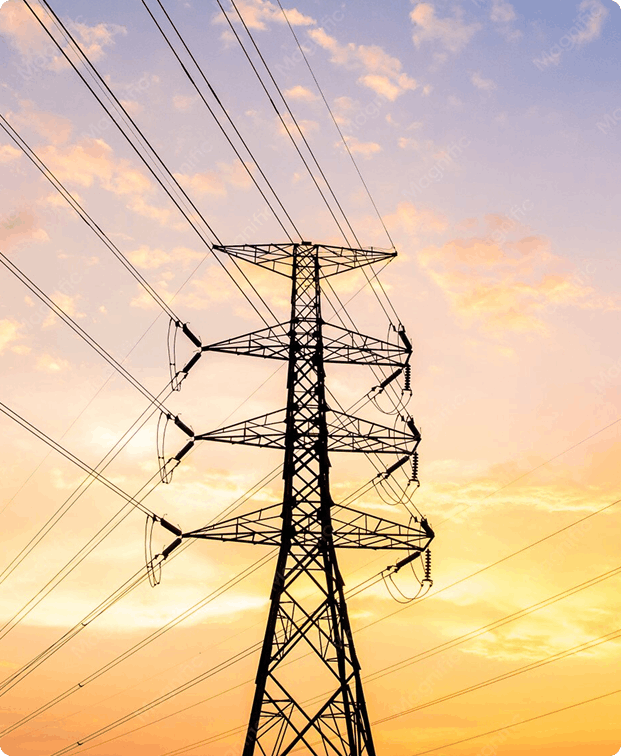 Transmission tower and several overhead power lines silhouetted against a warm sunset sky, electrical infrastructure