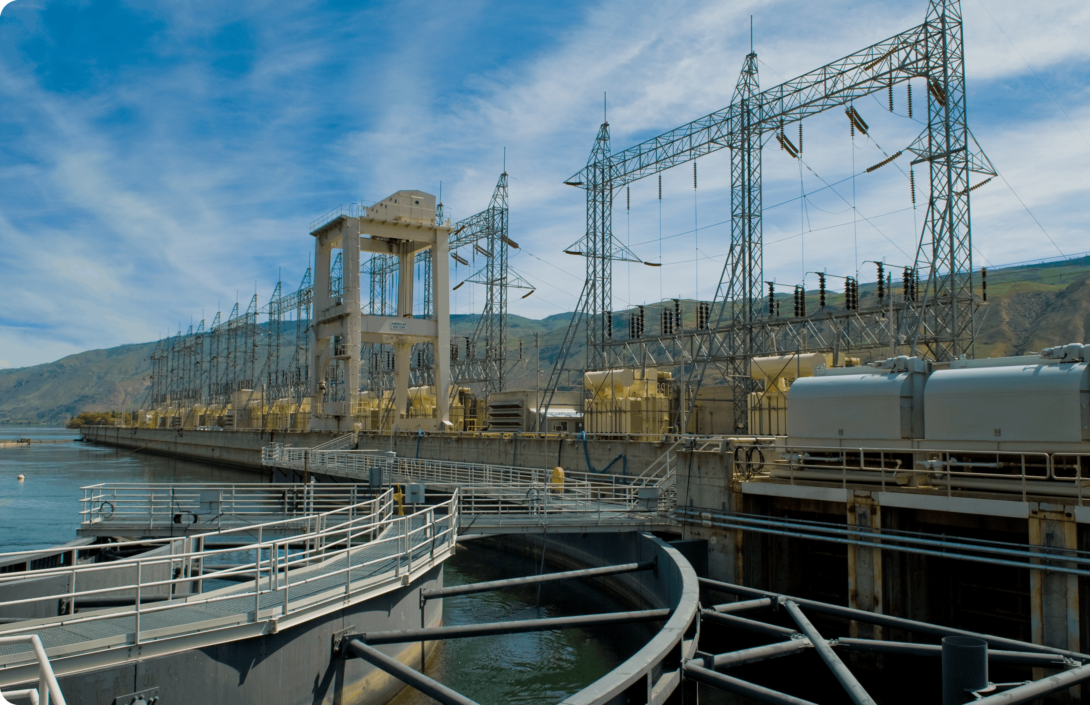 Dam intake and hydroelectric substation with fenced walkways, large transformers and lattice transmission towers