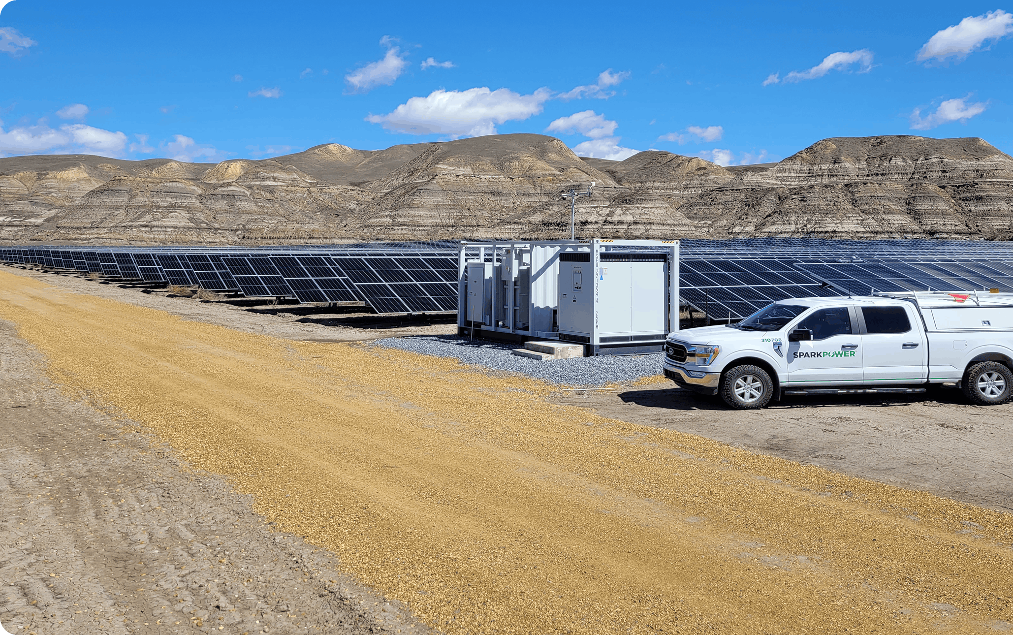 Utility‑scale solar farm with multiple PV panel rows, modular electrical equipment and SparkPower service truck