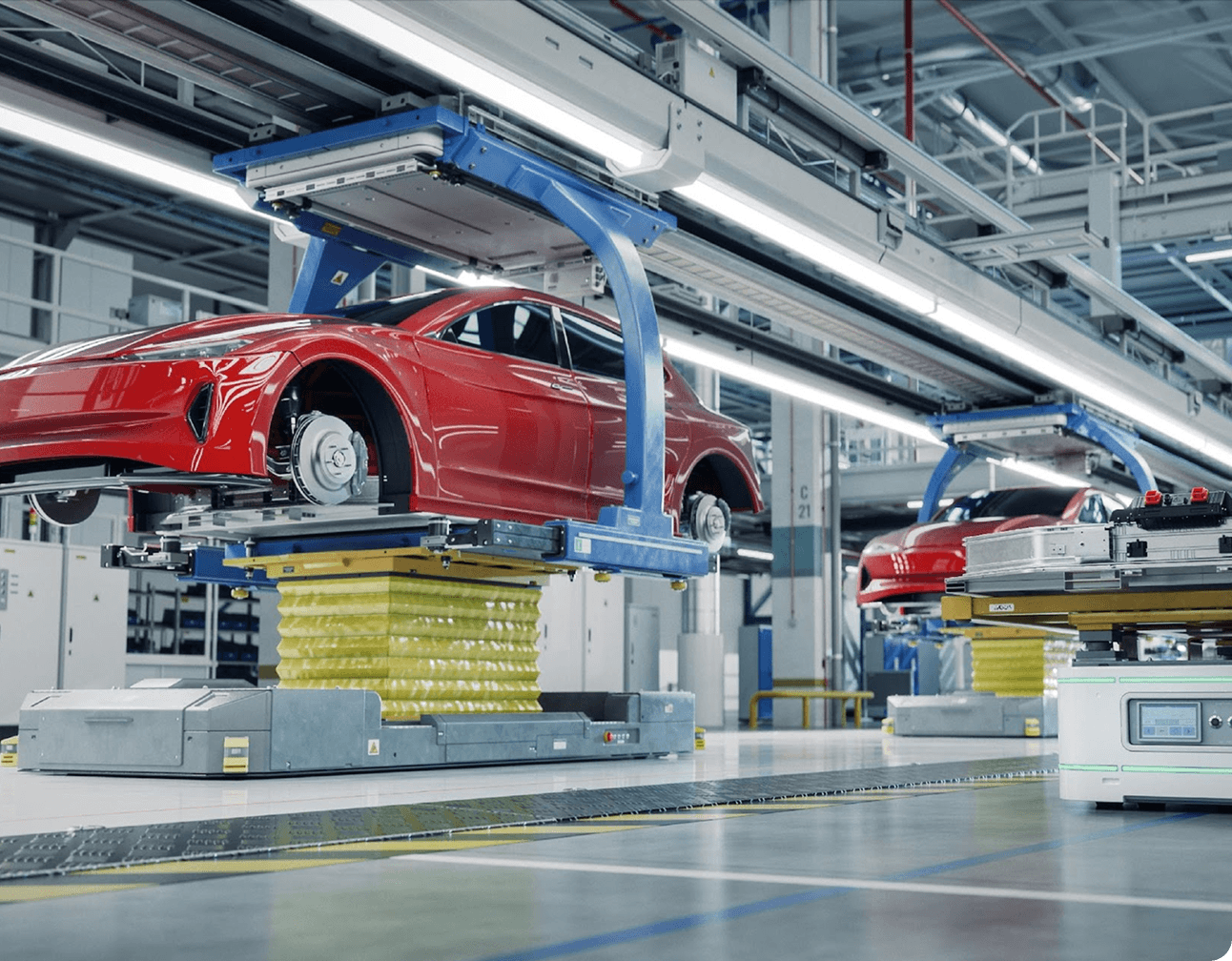 Red EV bodies on lifting platforms in a bright electric vehicle assembly line with robotic conveyors and equipment
