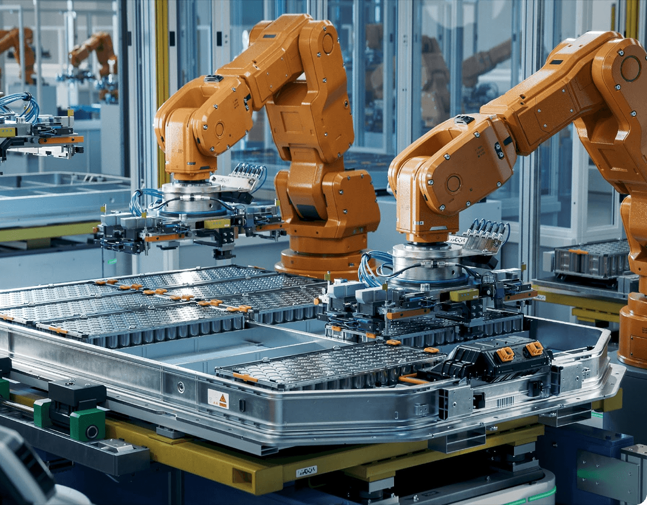 Orange robotic arms assembling battery packs into metal trays on an EV production line with automation tooling and cables